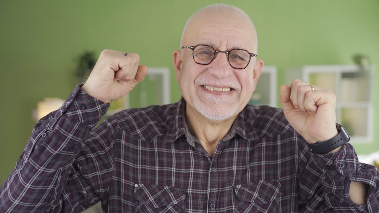 el viejo alegre se alegra en casa mirando a la cámara.