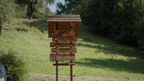 man walking past hikers signpost in beautiful green nature