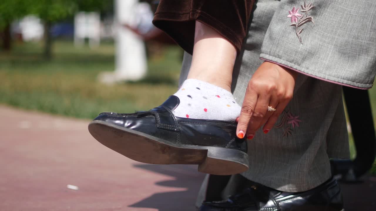 mujer con zapatos negros y calcetines blancos sentada en un banco en un parque