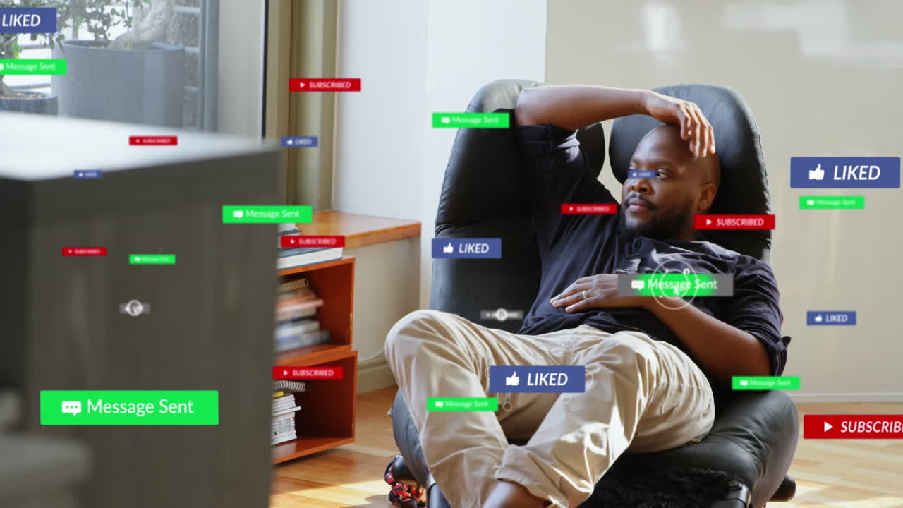 Animation of multiple social media icons over african american man looking out of window at home