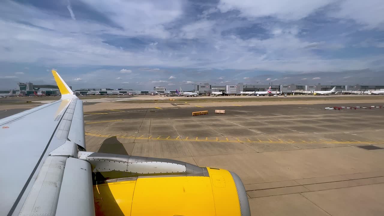 영국 런던 개트윅 공항에서 지상으로 움직이는 노란색 비행기 날개와 엔진의 전망