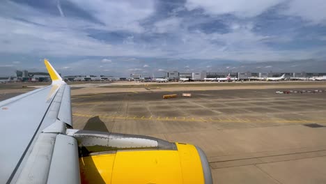 vista del ala de un avión amarillo y el motor en movimiento en tierra en el aeropuerto británico gatwick de londres en el reino unido