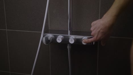 el hombre presiona el botón y la ducha se enciende