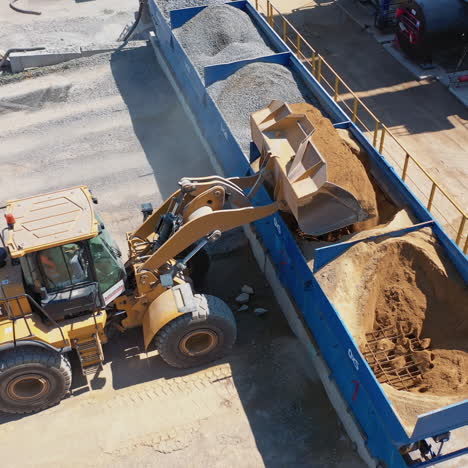 excavator on the territory of asphalt manufacture outdoors. modern excavator pouring out sand from bucket into a special tank. top view.