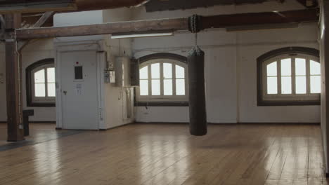 long shot of empty kickboxing gym with swinging punching bag