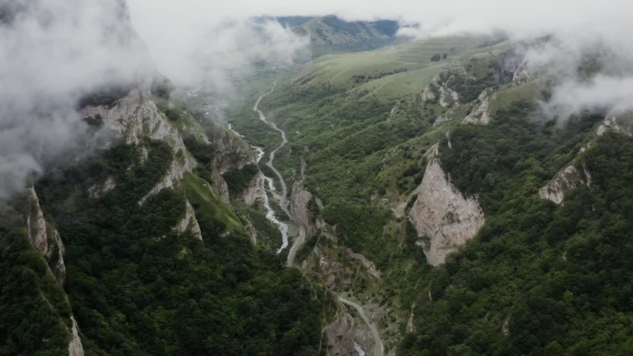 Valle de montaña con carretera sinuosa y niebla