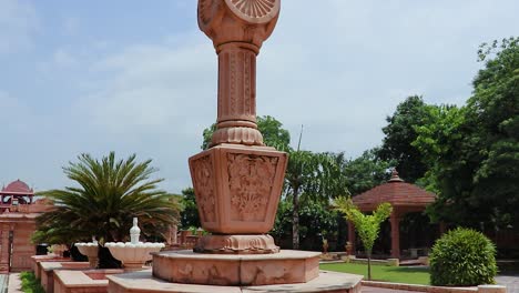 artistic-red-stone-jain-god-holy-pillar-with-bright-blue-sky-at-morning-from-unique-angle-video-is-taken-at-Shri-Digamber-Jain-Gyanoday-Tirth-Kshetra,-Nareli,-Ajmer,-Rajasthan,-India