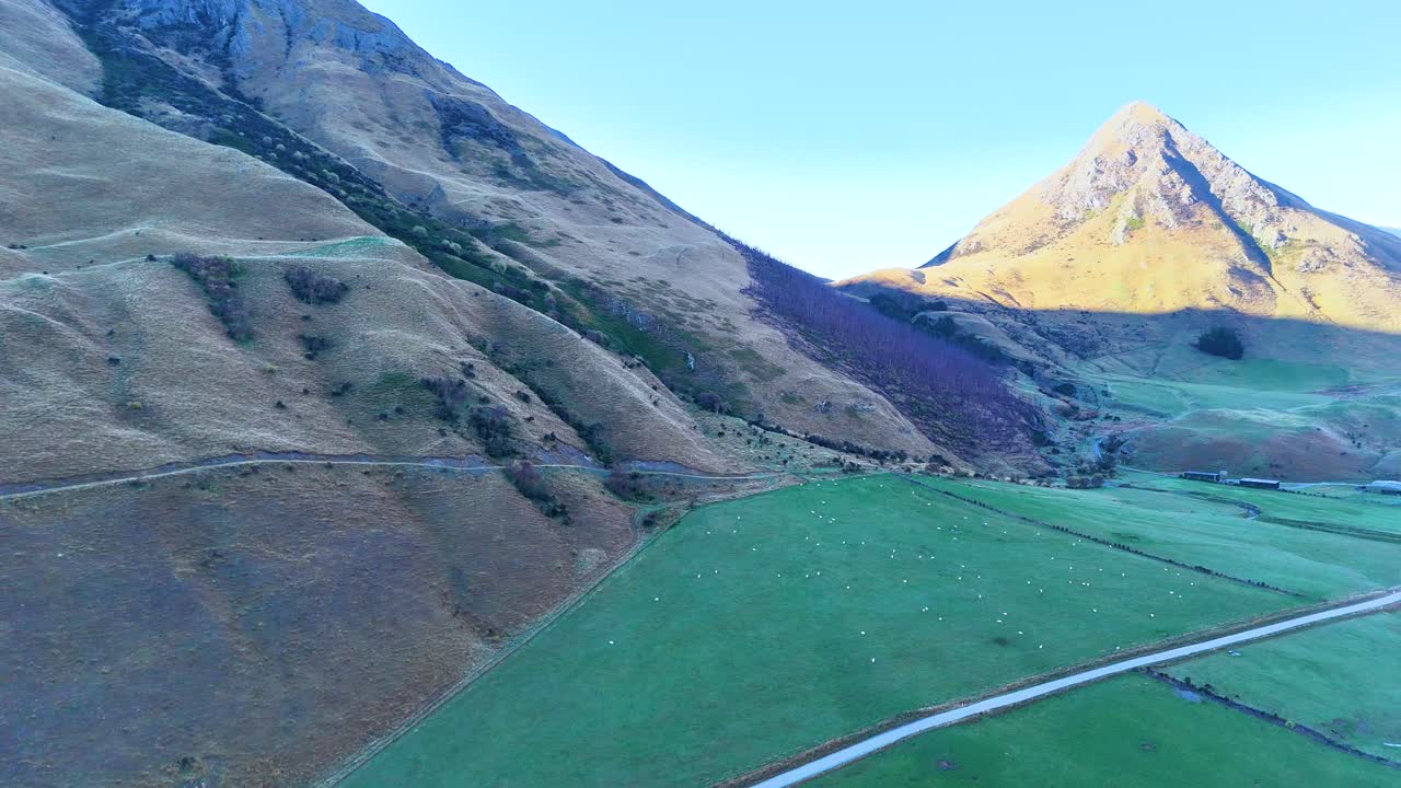 Drone footage captures Moke Lake's serene landscape with mountains in Queenstown, New Zealand, under clear blue skies and natural lighting
