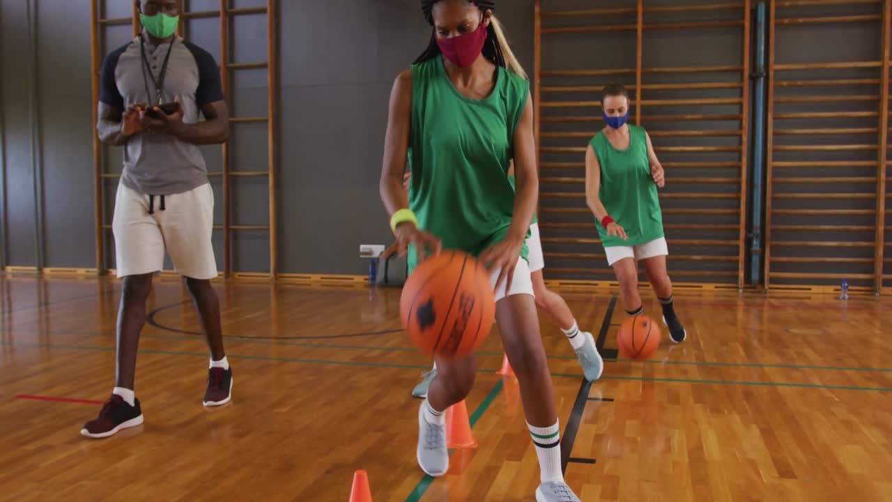equipo de baloncesto femenino diverso y entrenador con máscaras faciales practican el dribble de pelota