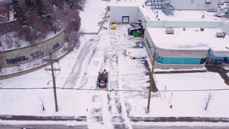 Aerial-of-snowplow-vehicle-removing-snow-on-city-road,-Montreal,-Canada