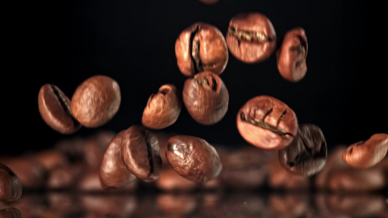 Chicchi di caffè tostati che cadono in super slow motion su sfondo nero