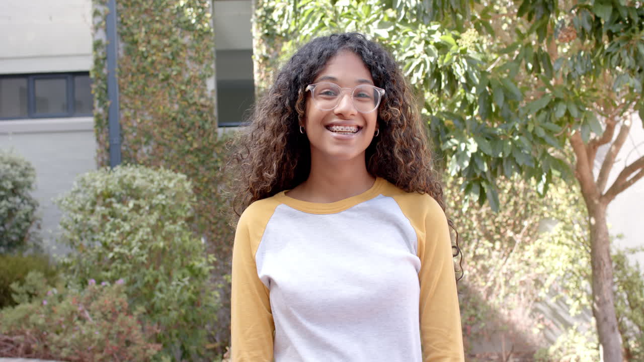 Smiling teenage girl stands outdoors