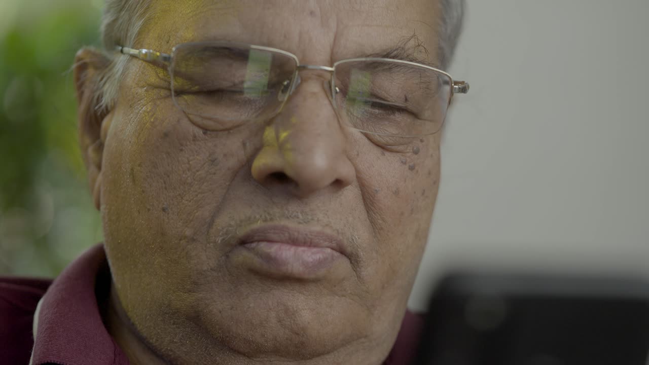 крупный план пожилого мужчины индийского происхождения азиатского происхождения, пользующегося мобильным телефоном