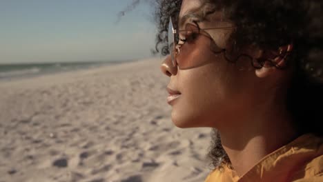 mujer con gafas de sol relajándose en la playa 4k