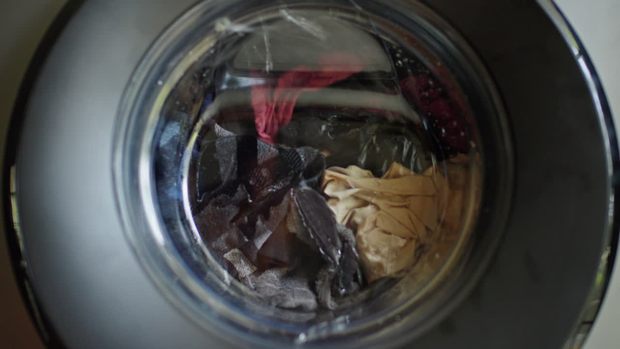 Laundry rotating inside washing machine drum during active wash cycle in modern household appliance