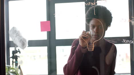 african american casual businessman drawing on glass wall at home office, copy space, slow motion