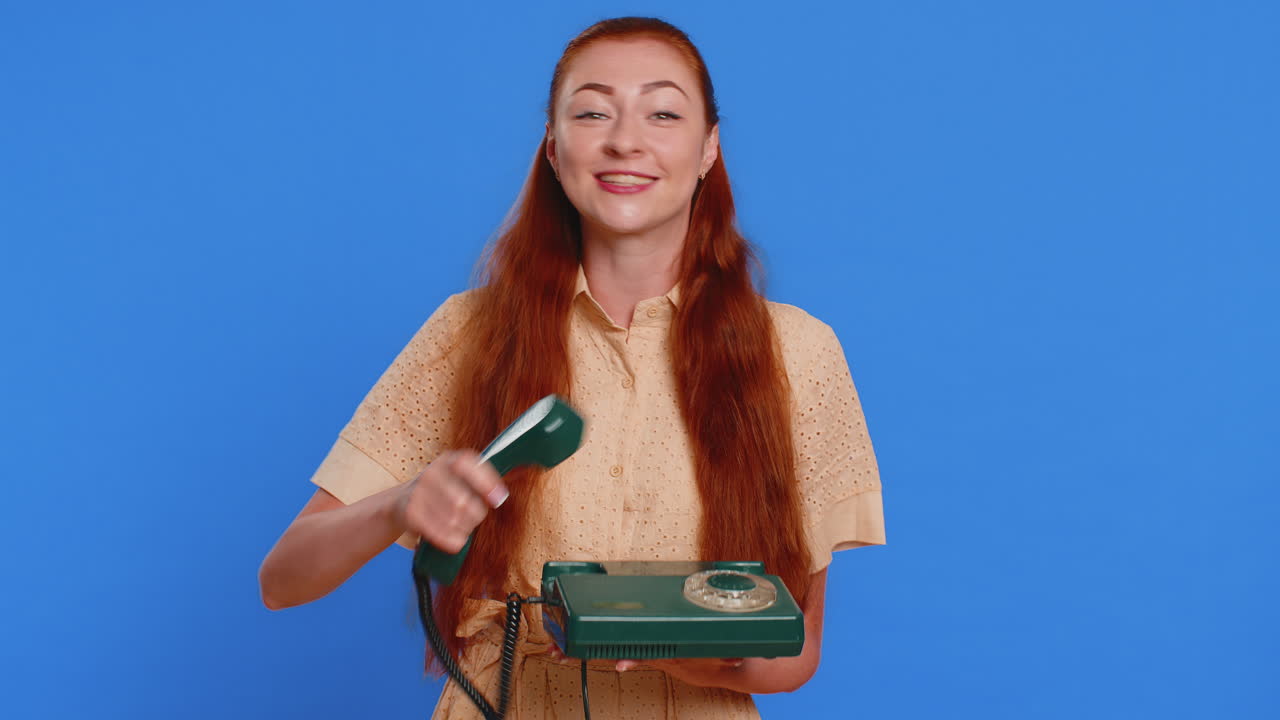 Rødhåret kvinde taler i en fastnet vintage telefon fra 80'erne, siger 'hej, ring mig tilbage' i en samtale
