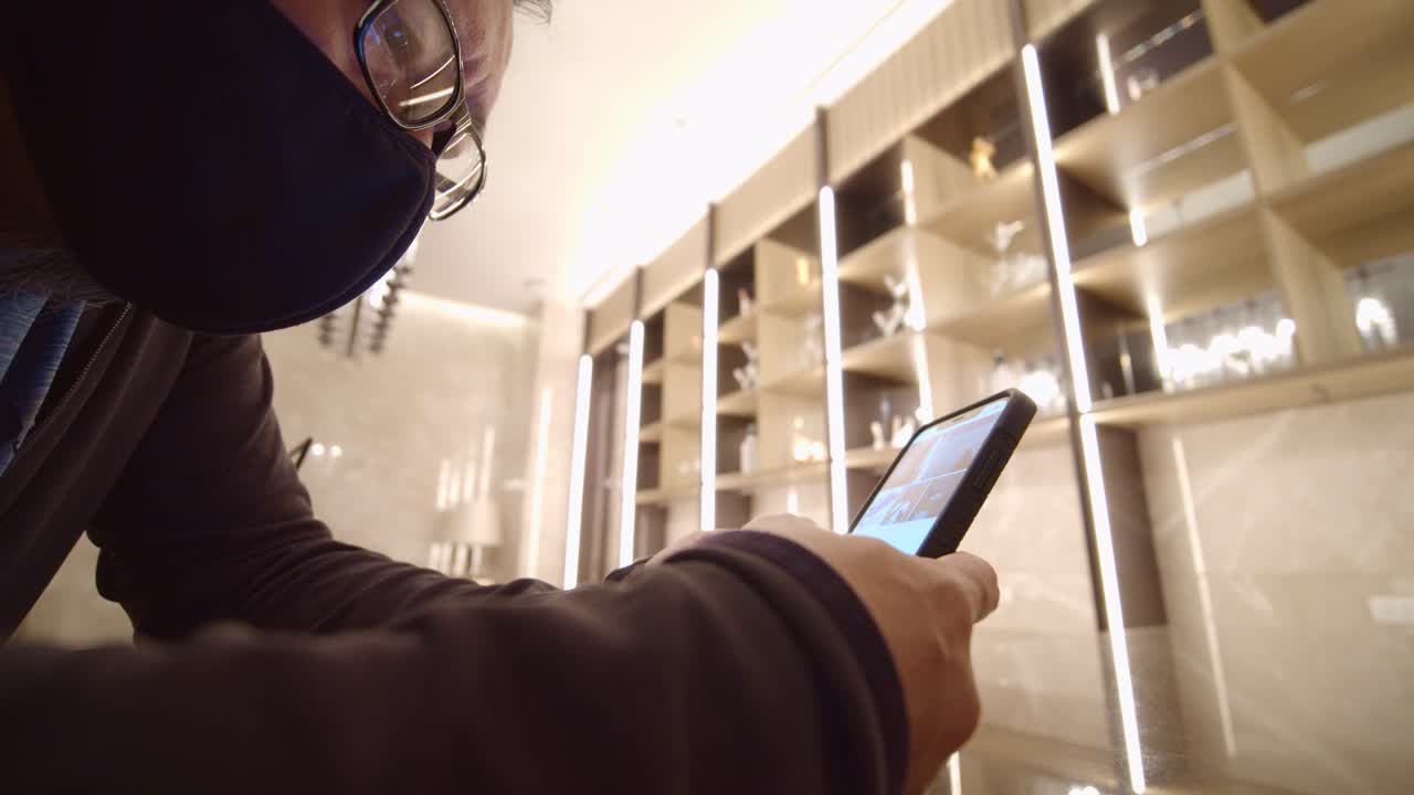 Man wearing a protective face mask plays with his smartphone - isolated view