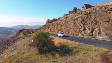 aerial shot of a car slowly moving on a mountain road