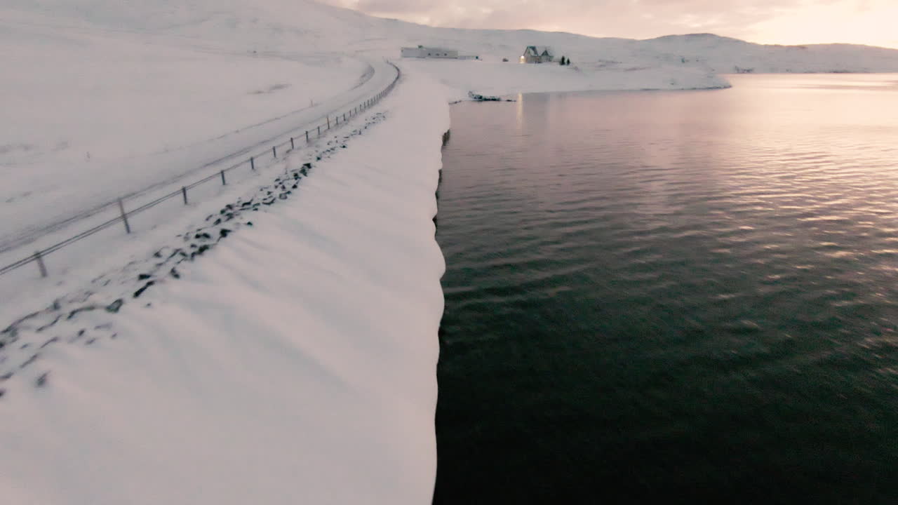 밝은 일출 동안 눈 덮인 해변이 있는 아름다운 시골 집