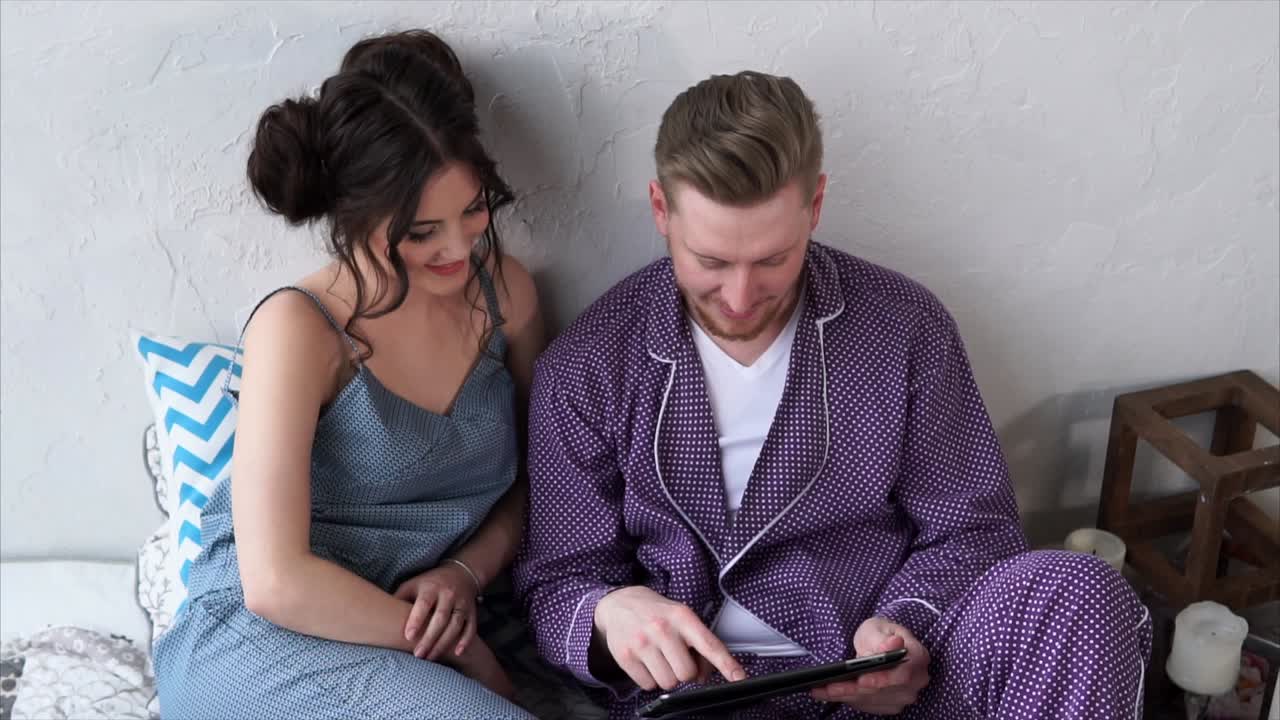 Couple using tablet in pajamas