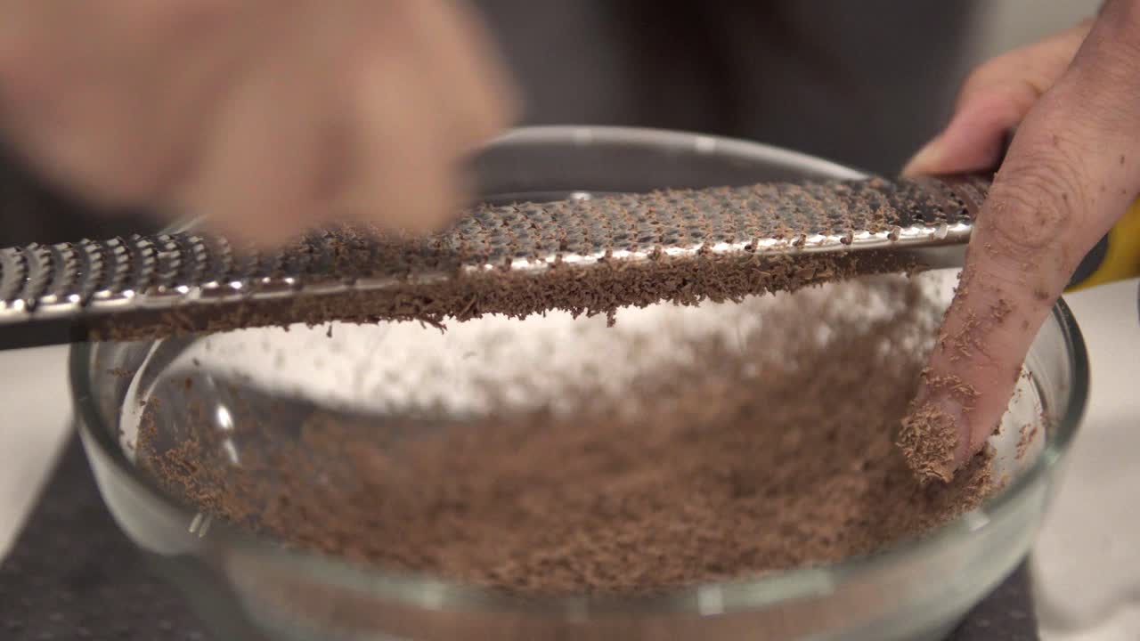 한 어린 소녀가 안전 장갑을 끼고 백만장자 쇼트브레드 쿠키를 만들면서 녹이기 위해 초콜릿을 그릇에 담습니다-1