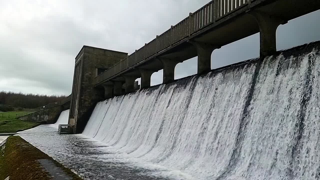 Cefni dam concrete barrier gate pouring slow motion water overflow from Llangefni, Anglesey reservoir
