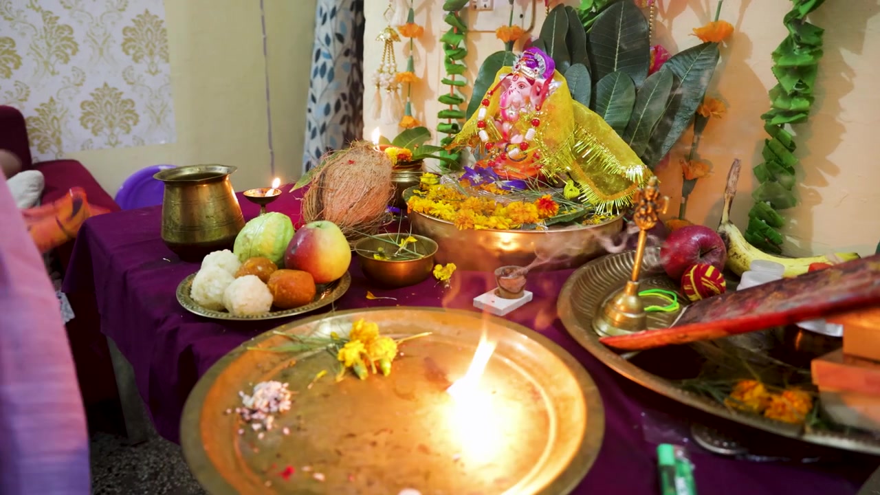 Những người phụ nữ đang thờ cúng với ngọn lửa aarti và các lễ vật Hindu trang trọng được bày biện trong lễ hội Ganesh Chaturthi.