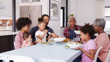 Familie-Mit-Mehreren-Generationen-Genießt-Das-Essen-Am-Tisch-Zu-Hause