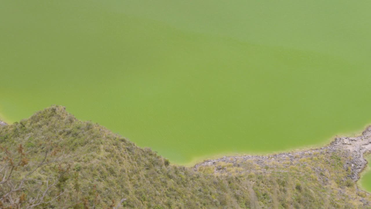 mirando por encima del borde para contemplar las aguas turquesas de la laguna de quilotoa dentro de la caldera, ecuador
