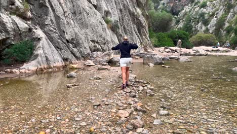 women walking balancing on rocks in sea, sa calobra mallorca, spain