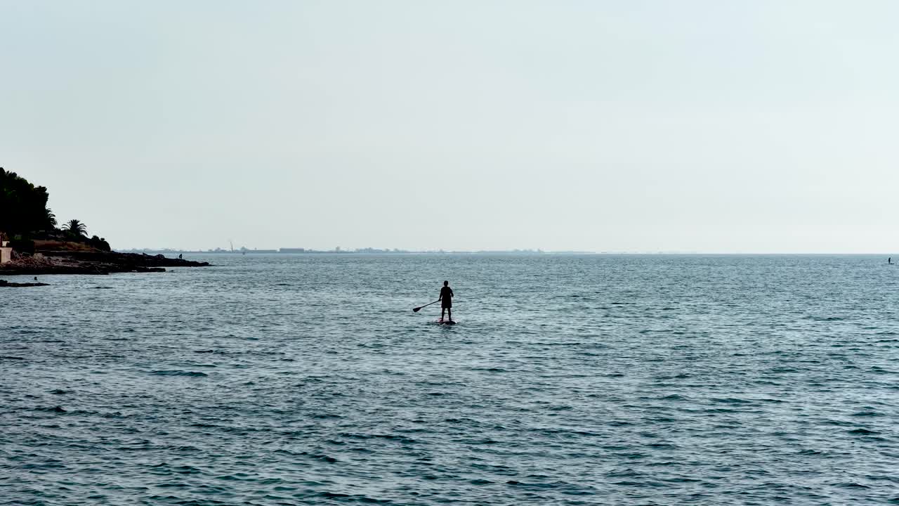 Man paddle boarding away from the coast