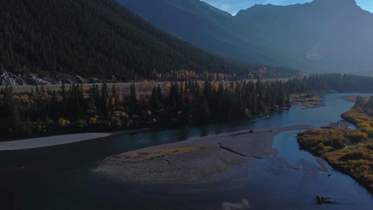 Highway in mountains by river with powerlines and parked car