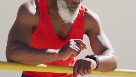 hombre afroamericano de alto nivel haciendo ejercicio tomando un descanso usando un reloj inteligente