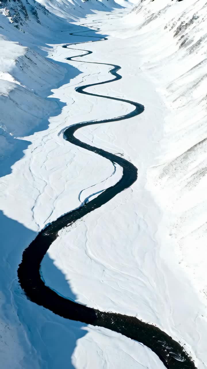 Aerial View of Winding River Through Snow-Covered Mountain Valley