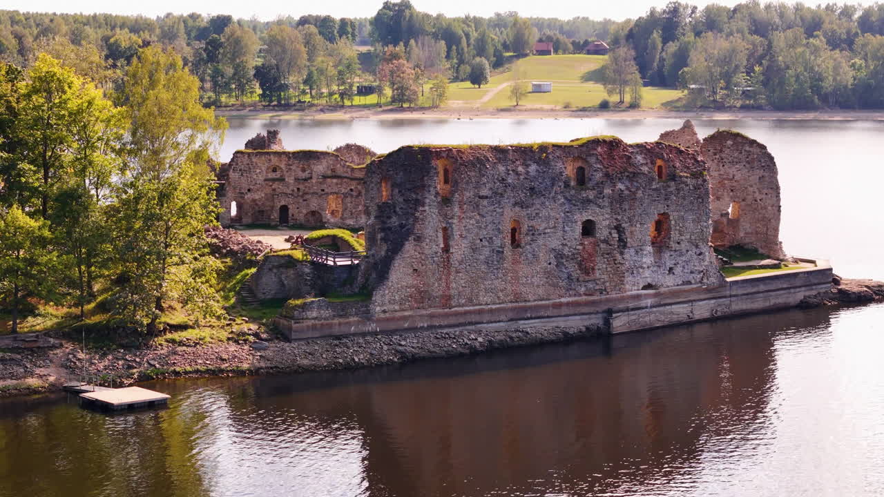 Drone footage of Koknese Castle ruins with reflections in the calm Daugava River.