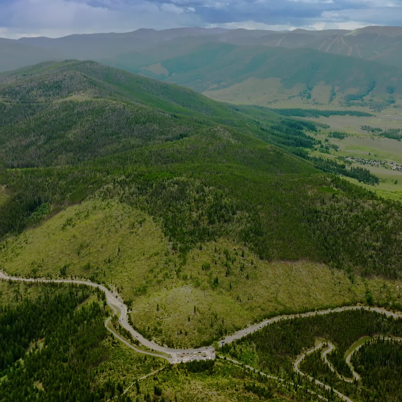 Sinuate road going round the hill covered with pine trees. Scenic picture of beautiful mountains of Colorado, USA. Aerial view