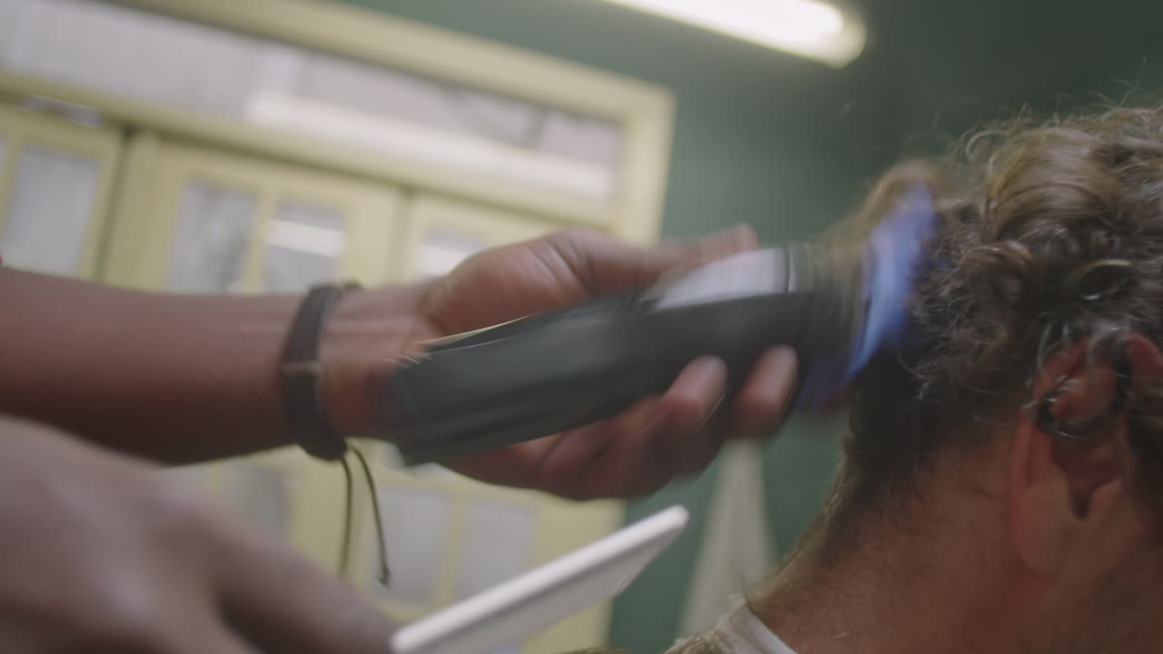 Barber Trimming Neckline with Hair Clippers and Comb