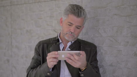 hombre maduro serio usando teléfono móvil