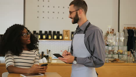 african woman making an order to caucasian waiter in a coffee shop