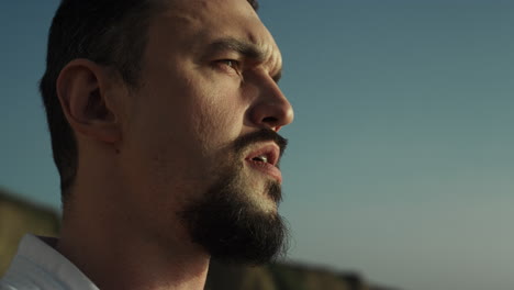 Thoughtful-sportsman-face-watching-sunset-on-beach.-Man-resting-after-training.