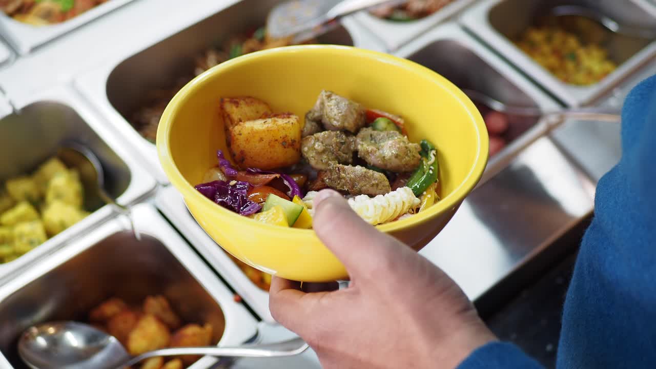 persona que se sirve una comida de una línea de buffet