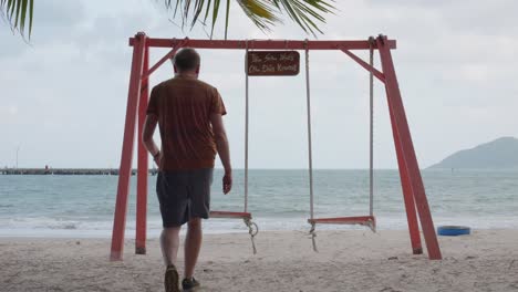 hombre caminando hacia el columpio en la playa bai tam an hai en un día ventoso