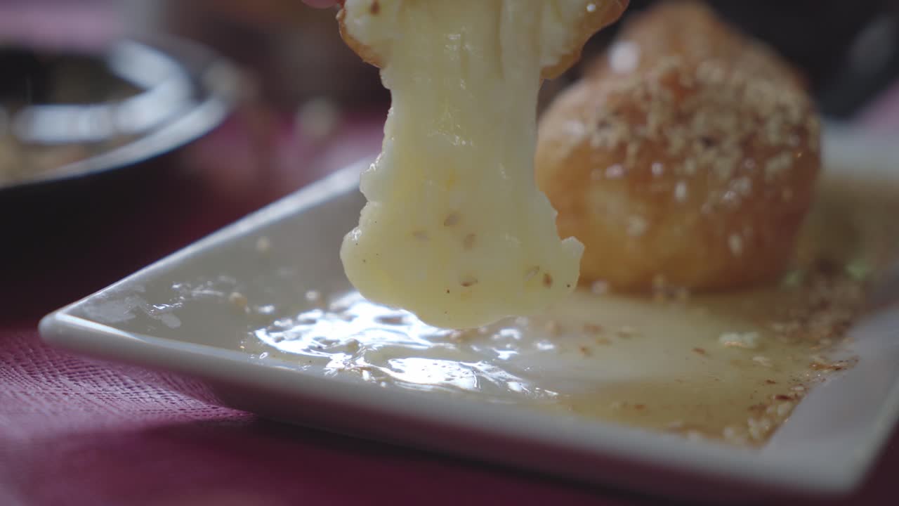hot cheese oozing from Greek Honey balls when picked up by a restaurant patron