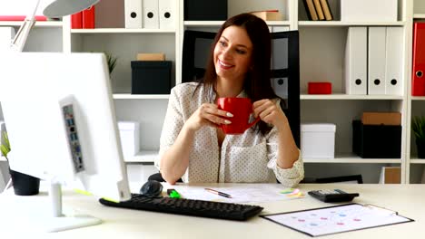 mujer de negocios con copa mirando en el monitor en la oficina