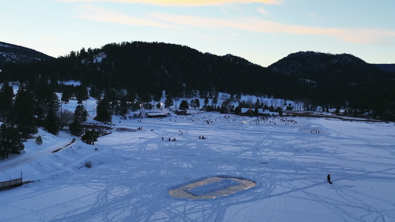 Evergreen Lake house January mid winter ice skating, pond hockey and ice fishing under lights sunset Colorado cinematic forward motion