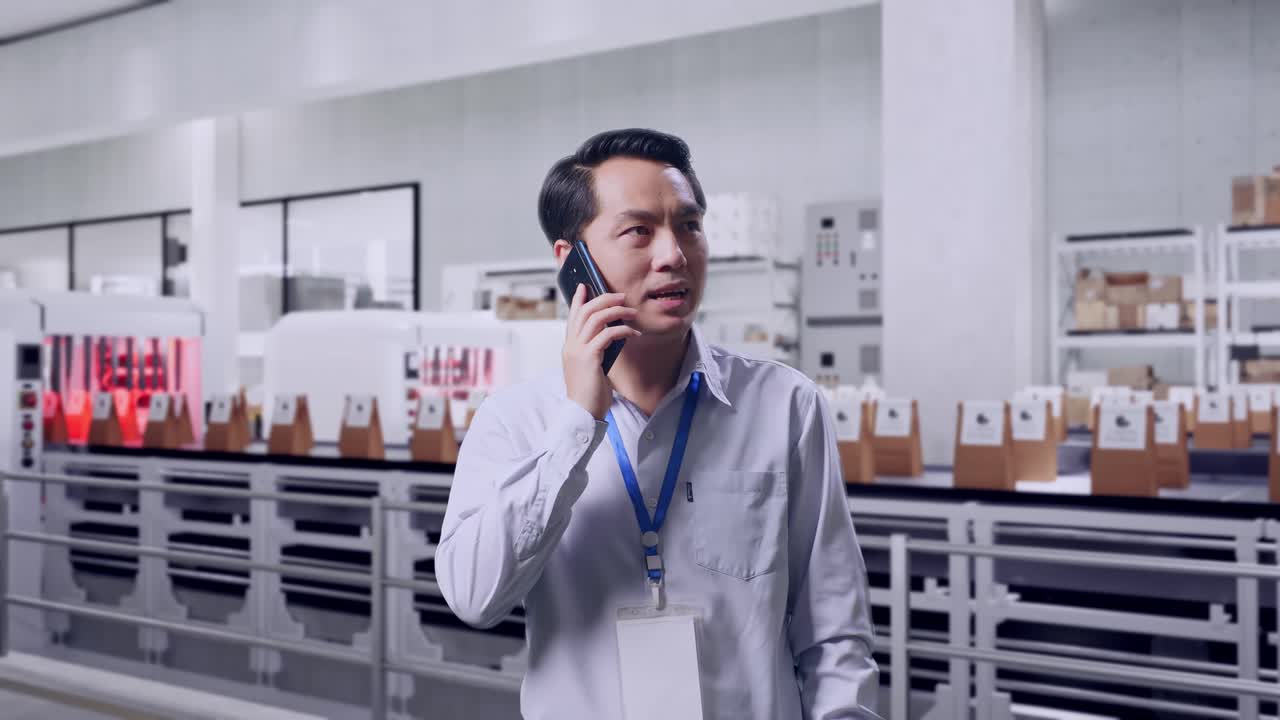 Asian Male Professional Worker Standing With Conveyor for Packaging Coffee Beans in Bags at Coffee Factory, He Pick The Phone Up And Started To Speaking With It