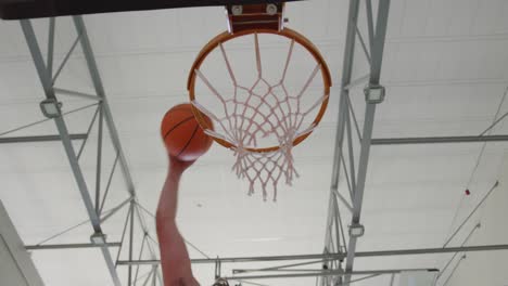 Caucasian-male-basketball-player-scoring-goal-during-match