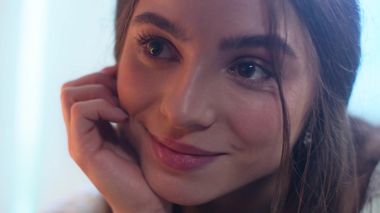 Primo piano di una giovane donna che sorride con un'espressione serena.