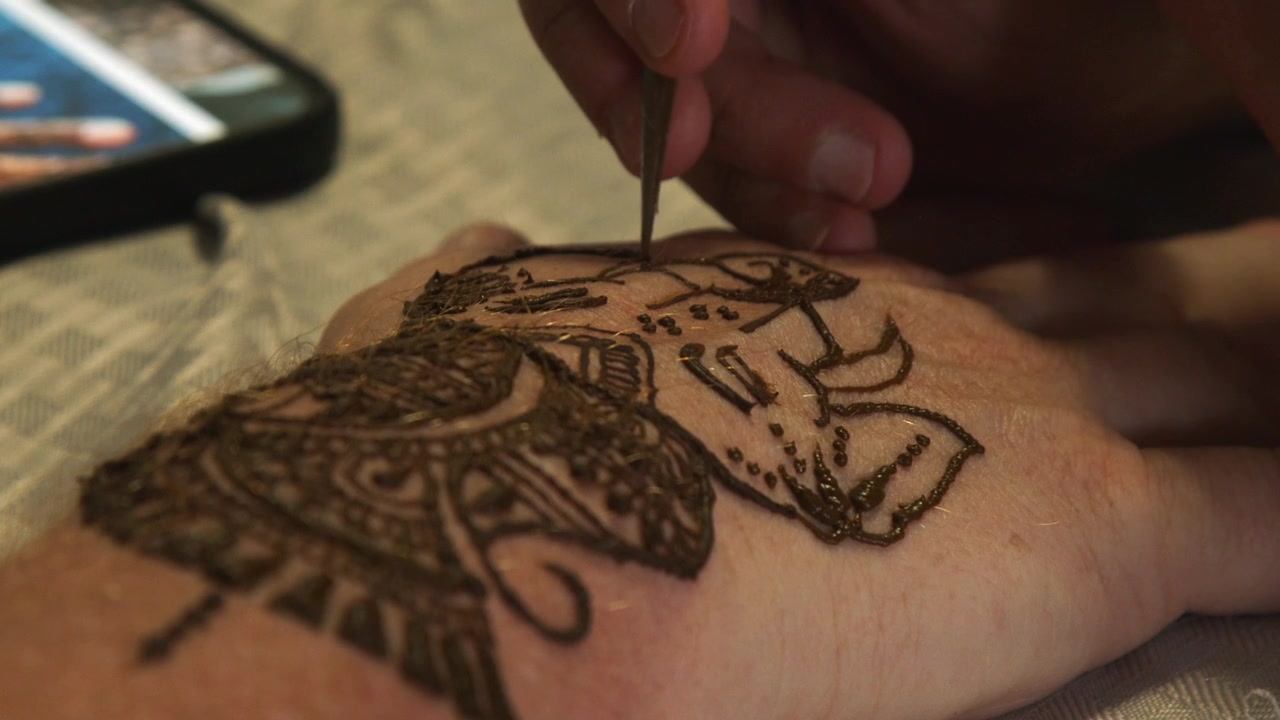 Zanne di Ganesha disegnate sulla mano di un uomo con tintura all'henné marrone, arte temporanea.